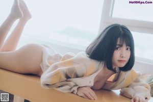 A woman sitting on top of a couch next to a window.