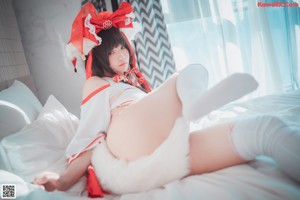 A woman in a red and white outfit sitting on a bed.