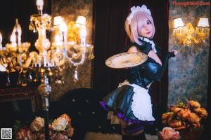 A woman in a maid outfit sitting on the floor next to a clock.