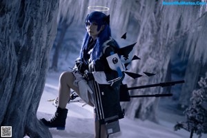 A woman with blue hair sitting on the floor.