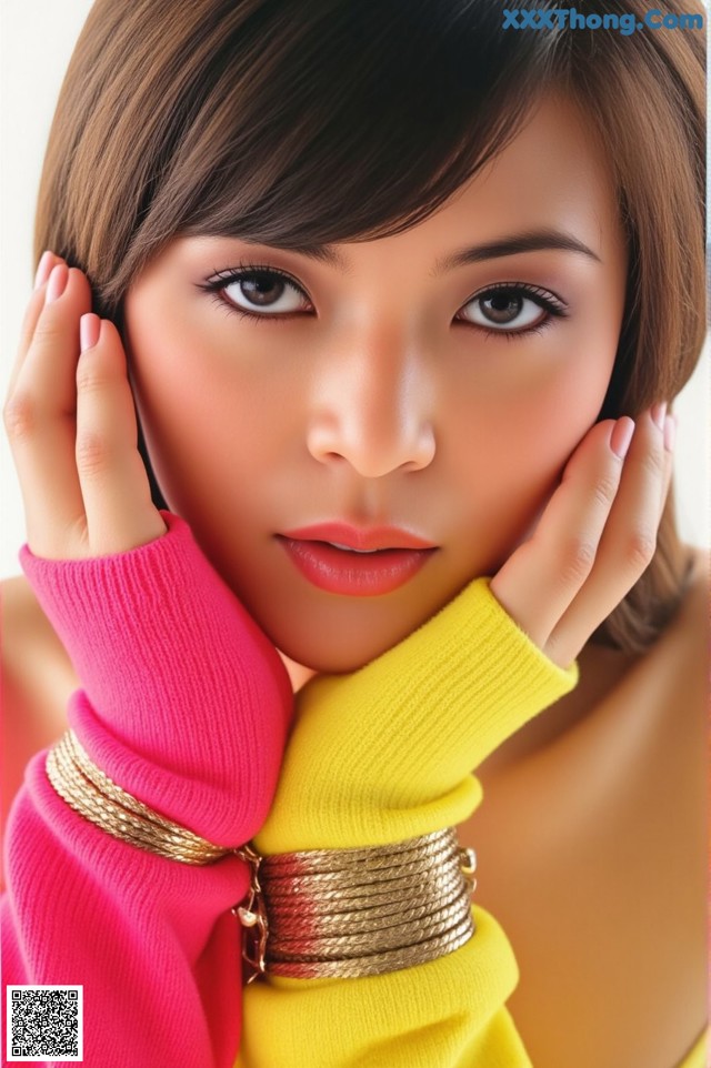 A woman in a pink and yellow sweater posing for a picture.