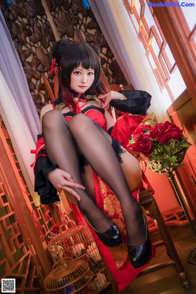 A woman in a red and black dress sitting on a chair.