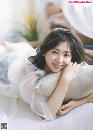 A young woman laying on a bed with her head resting on her hand.