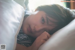 A woman laying on top of a white bed.