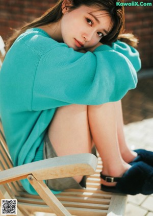 A woman in a blue sweater leaning on a white table.