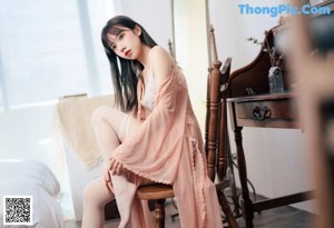 A woman sitting on a chair in a white lingerie.