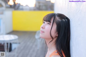 A woman in an orange dress looking up at the sky.