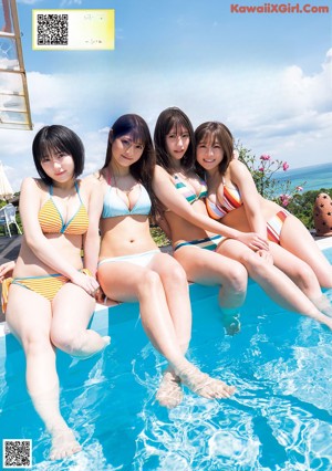Two young women in bikinis sitting on a sandy beach.
