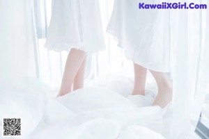 A woman in a white dress laying on a bed.