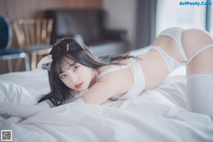 A woman in a white lingerie laying on a bed.
