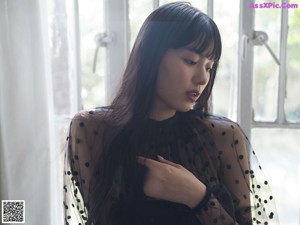 A woman sitting on a window sill in a black dress.