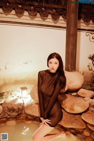 A woman in a black bodysuit and high heels posing for the camera.