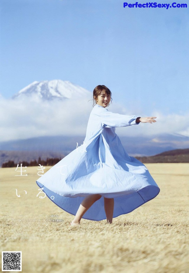A woman in a blue dress standing in a field.
