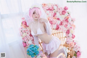A woman with pink hair sitting on a wicker chair.