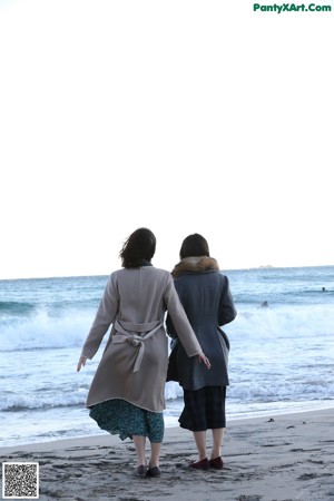 A couple of naked women standing next to each other in a pool.