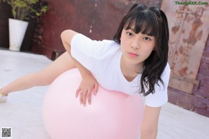 A woman in a white shirt and blue shorts holding a water gun.