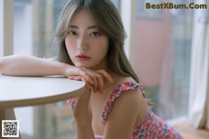 A woman sitting on a wooden floor next to a chair.