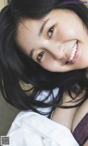 A woman with long black hair laying on a bed.