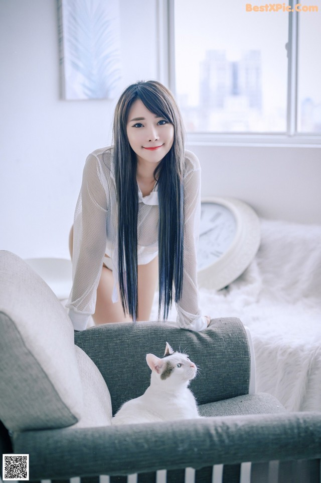 A woman sitting on a couch with a cat on her lap.