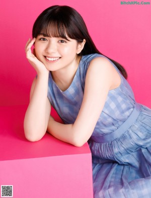 A woman with long black hair and bangs is posing for a magazine.