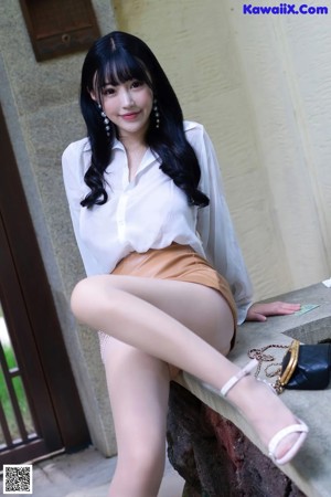 A woman in a white shirt is putting on a pair of shoes.