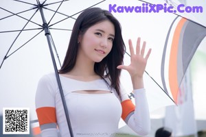 A woman holding an umbrella standing next to a white car.