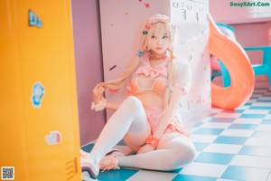 A woman in a pink outfit is sitting on a blue and white checkered floor.