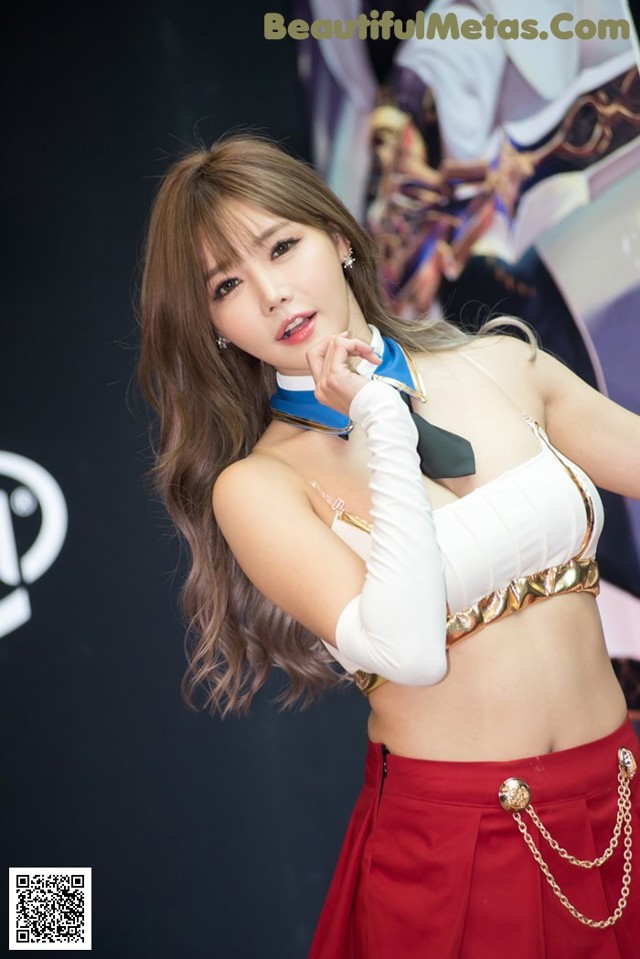 A woman in a white top and red skirt posing for a picture.