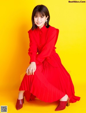 A woman in a red dress sitting on a yellow table.