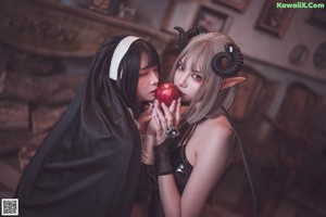 A couple of women dressed up as vampires eating an apple.