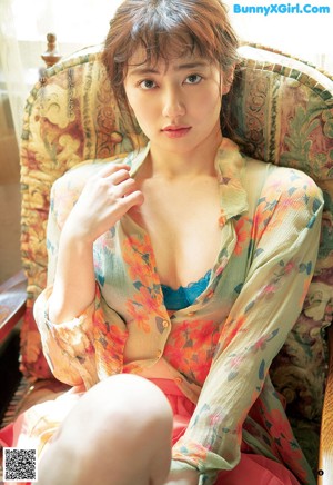 A woman in a black lingerie sitting on a window sill.