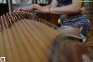 A woman in a blue dress playing a musical instrument.